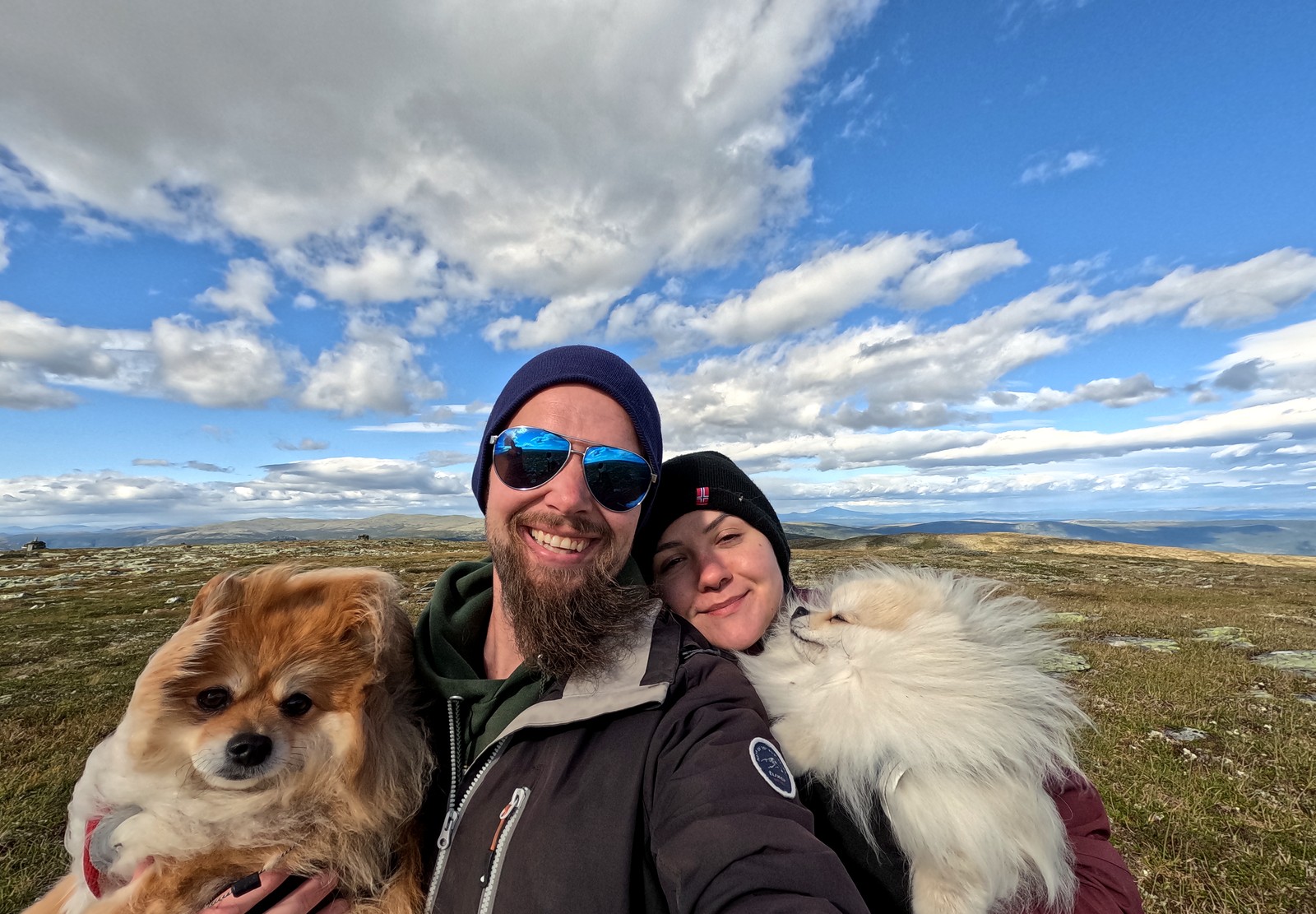 Erlend smiling with his partner and two dogs in the Norwegian mountains