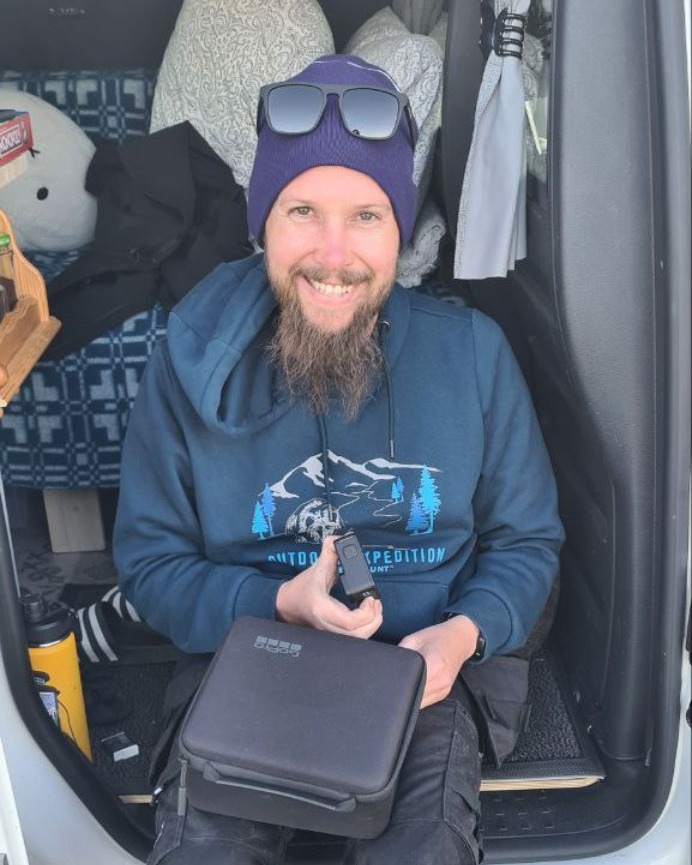 Erlend smiling while seated in the doorway of his van